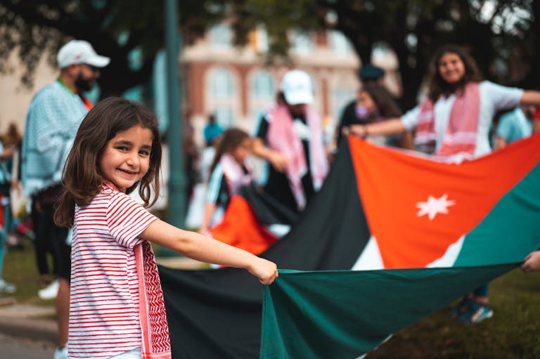 coscienza A cheerful girl holds a flag during a lively outdoor protest, celebrating cultural identity.